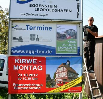 Plakatständer gegenüber Blauem Haus zwischen den Ortsteilen