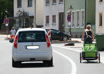 Auto und Kinder-Rad-Anhänger auf Schutzstreifen