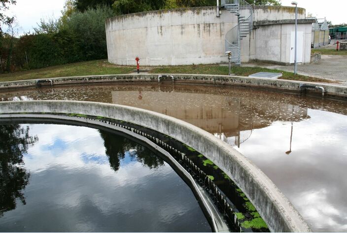Im äußeren Ring der beiden großen Becken ist das Belebungsbecken und innen das Nachklärbecken, wo das Wasser zur Ruhe kommt und sich Schlamm absetzen kann, der abgesaugt wird. Zwischen beiden ist die Überlaufrinne, in welche Wasser vom Nachklärbecken fließt. Das Wasser durchläuft beide Becken mehrfach, bevor es abgeleitet wird. Im Hintergrund ist einer der drei Silos zu sehen, in welchem der Schlamm gelagert und vorentwässert wird, bevor er abtransportiert wird.