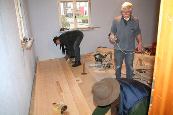 Dieter Fuchs, Wolfgang Knobloch und Siegfried Stutz beim Verlegen des massiven Dielenbodens aus schwedischem Holz.